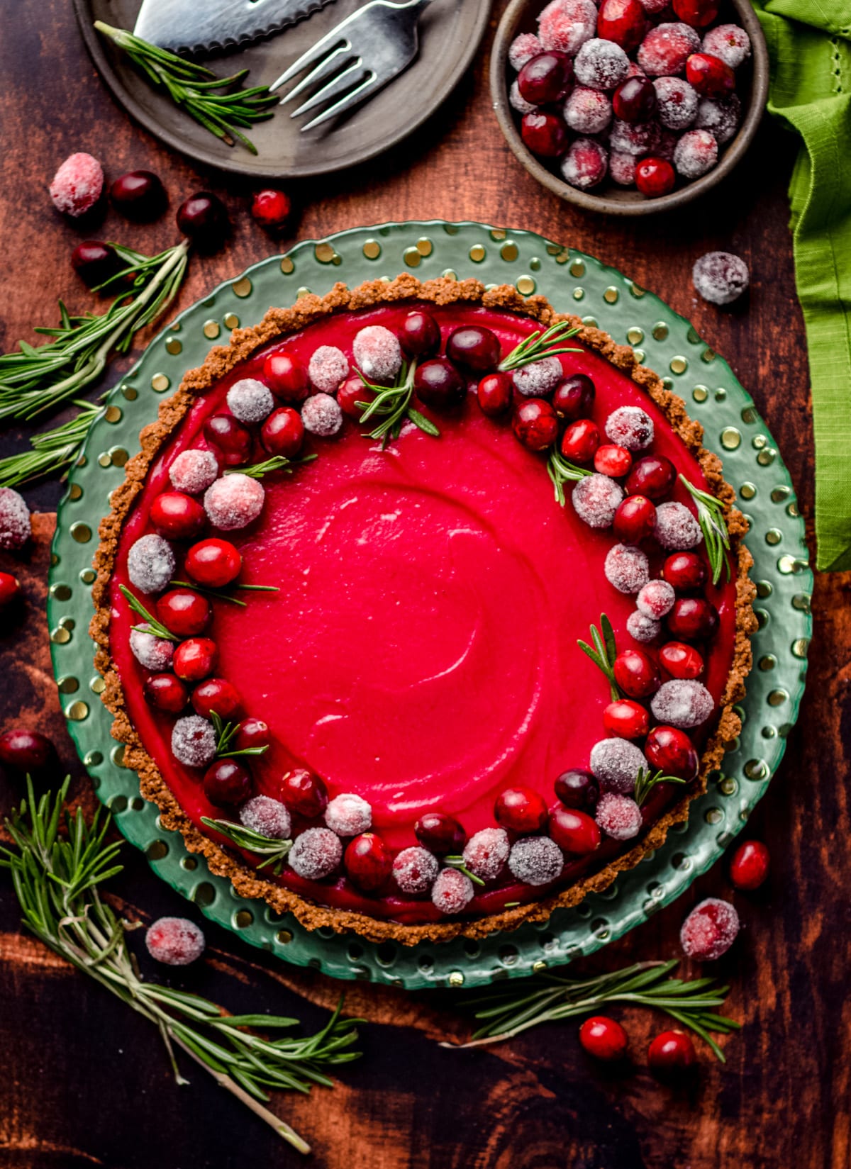 An overhead of a tart filled with cranberry curd and garnished with sugared cranberries.