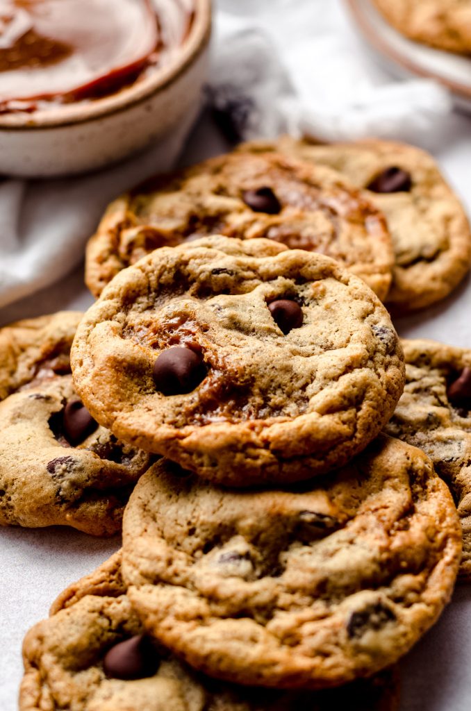 A pile of cookies with a bowl of dulce de leche in the background.