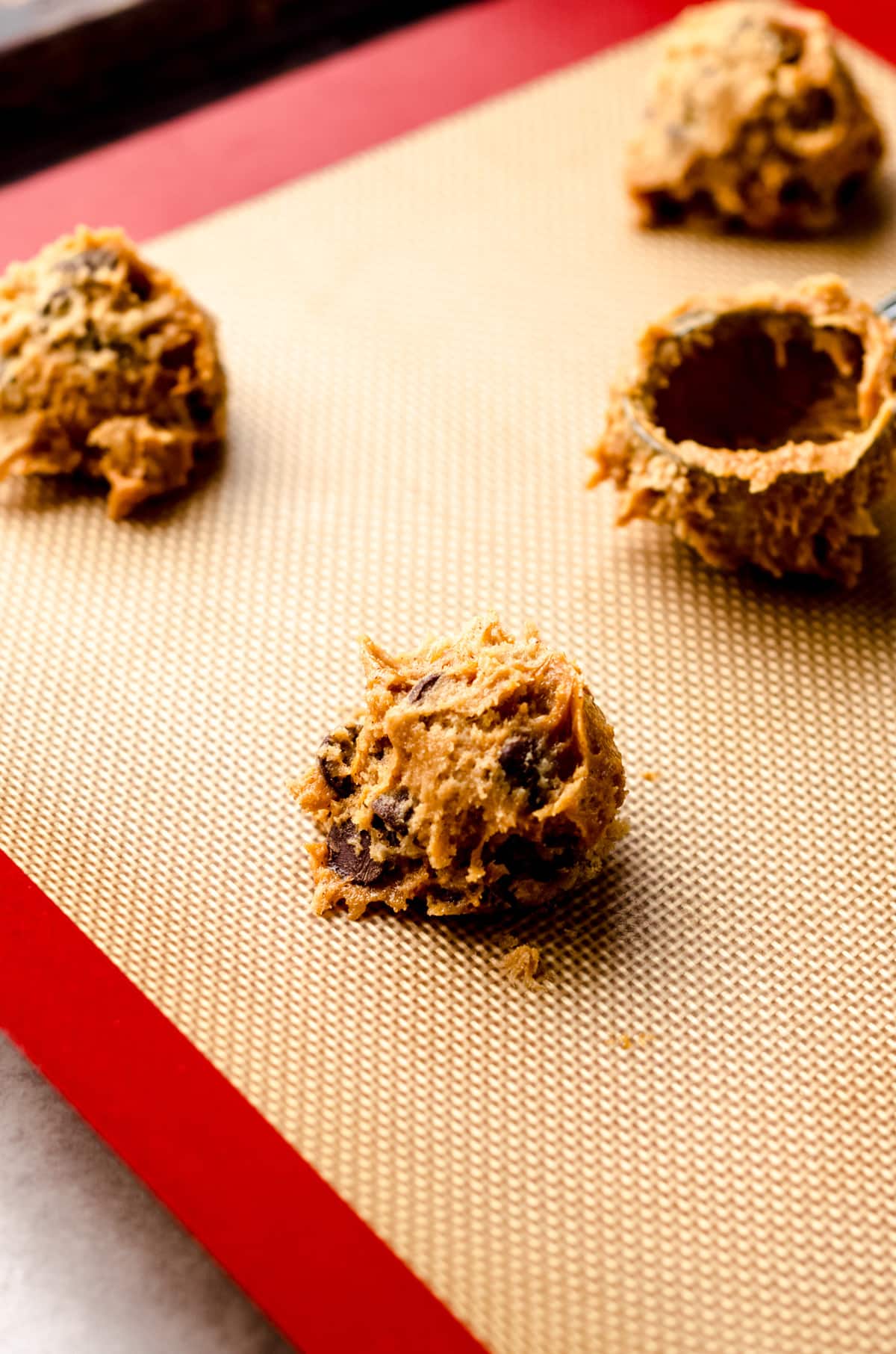 Placing scoops of cookie dough on a prepared baking sheet.