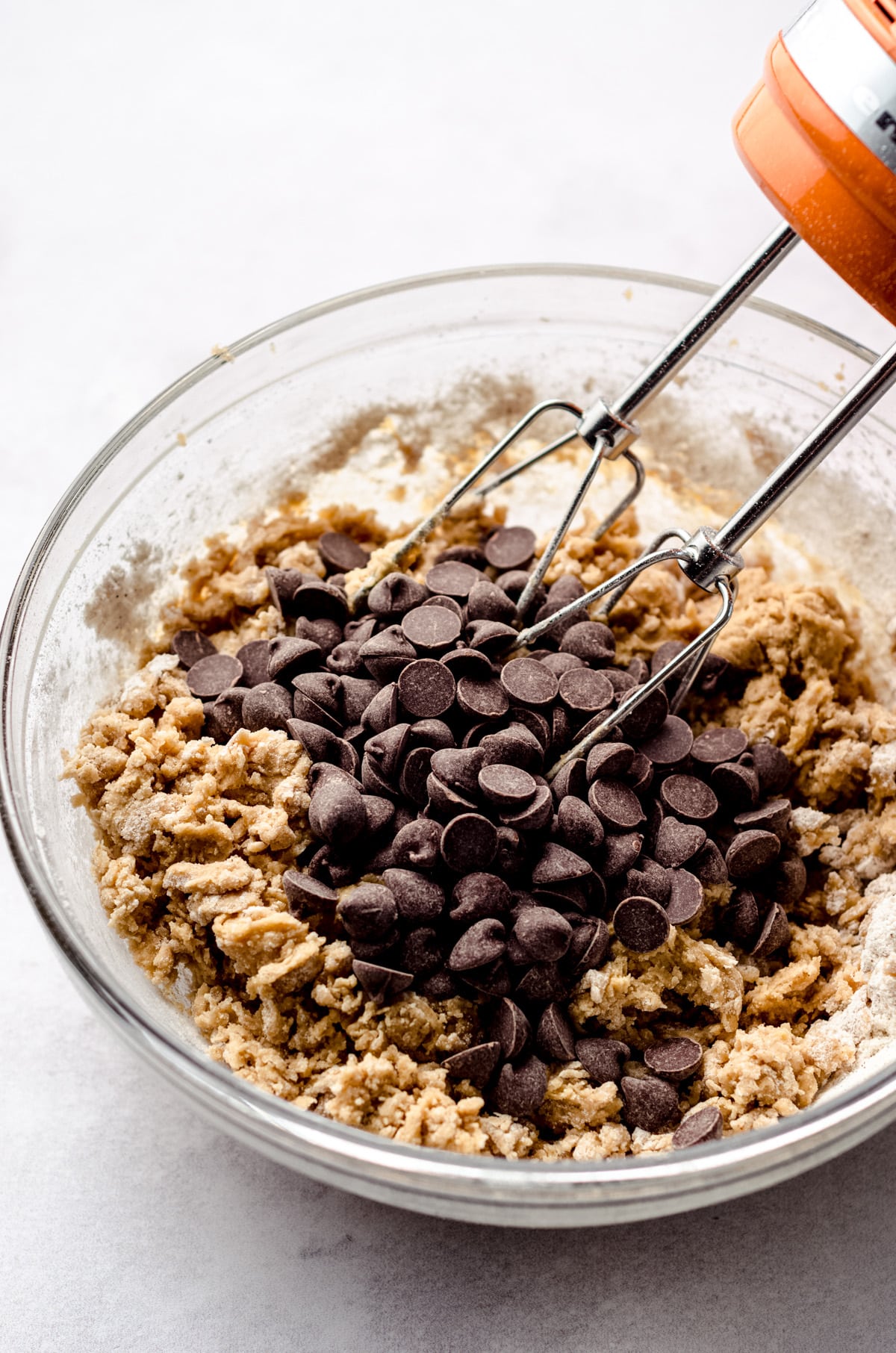 Adding chocolate chips to a cookie dough base and mixing them in.