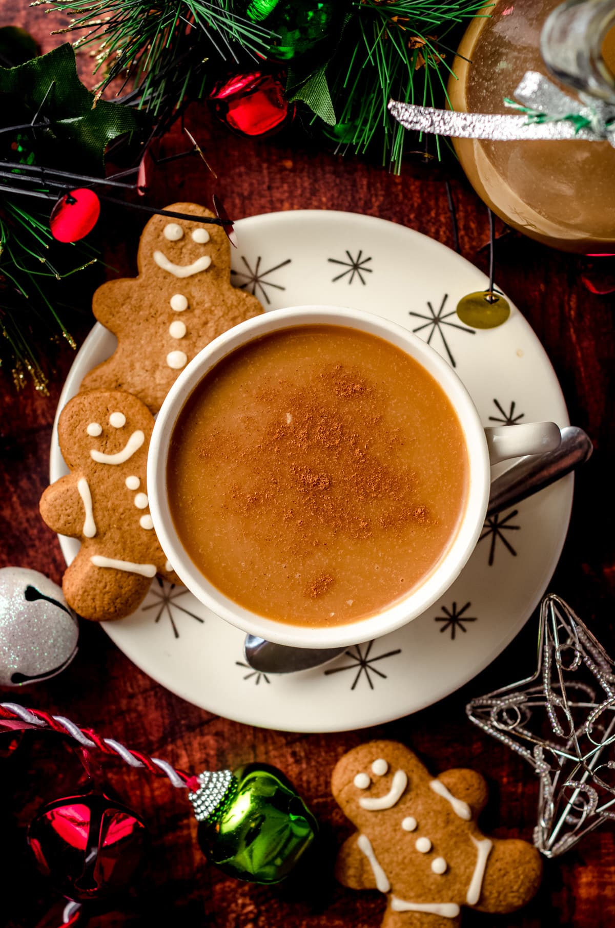 aerial photo of a cup of coffee with gingerbread coffee creamer and gingerbread cookies on the saucer