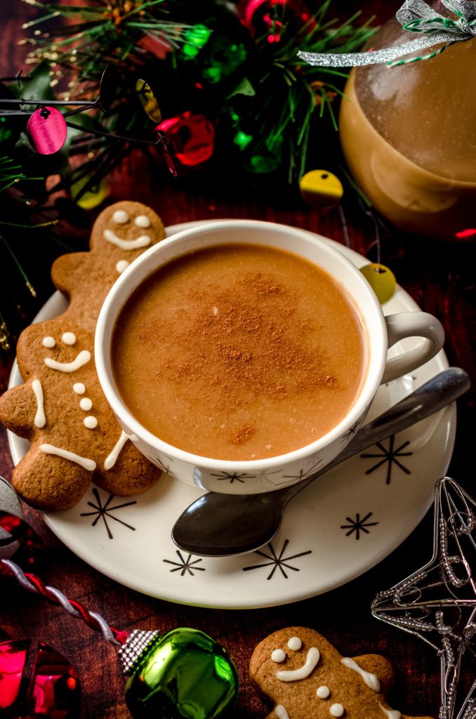 cup of coffee with gingerbread coffee creamer and gingerbread cookies on the saucer