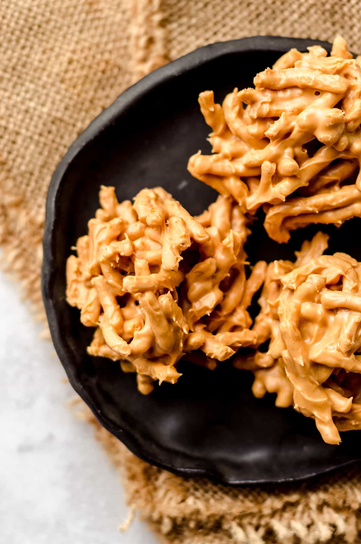 A black plate with three haystack cookies.