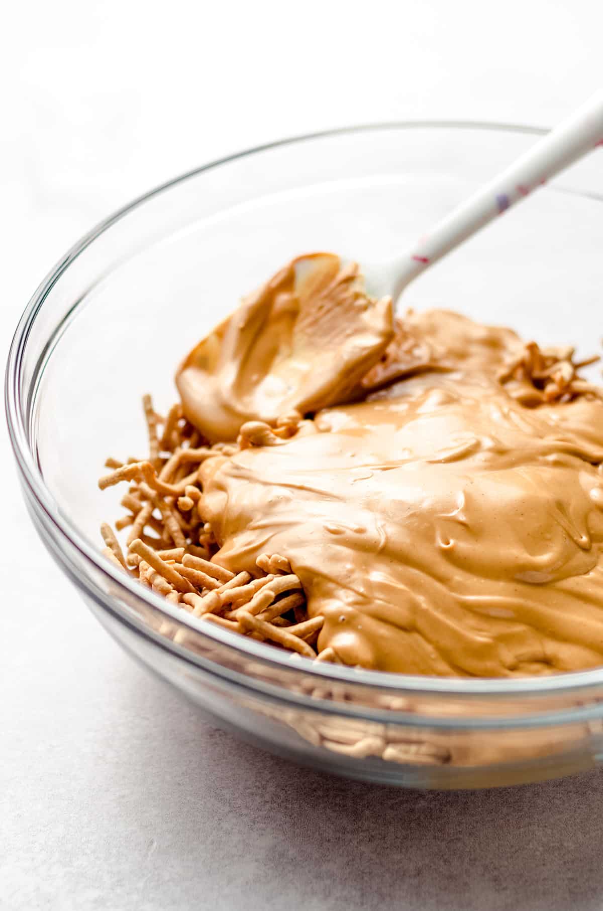 Adding melted butterscotch chips and peanut butter on top of chow mein noodles.