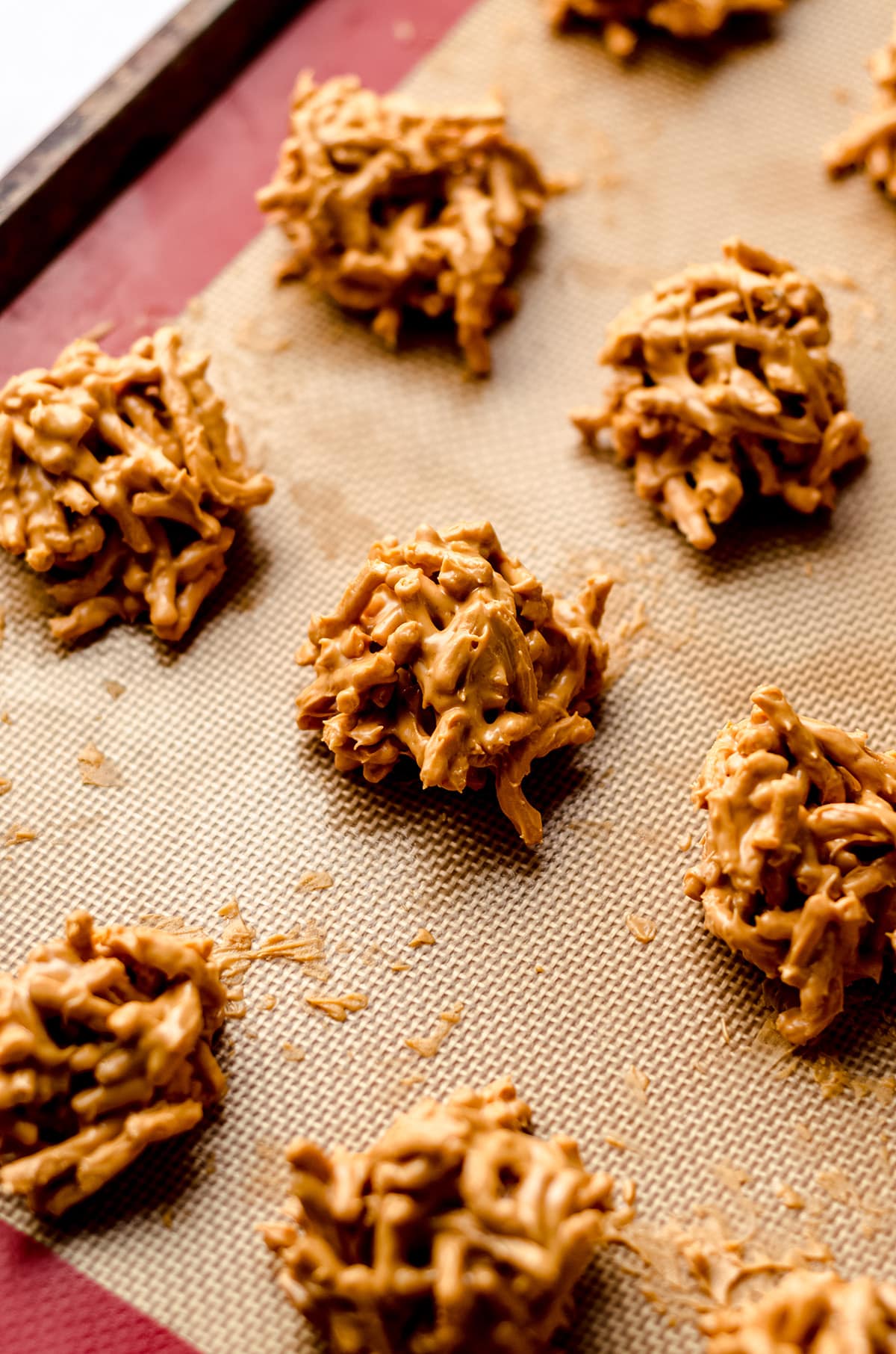 A silicone baking mat with mounts of no bake cookies on it.