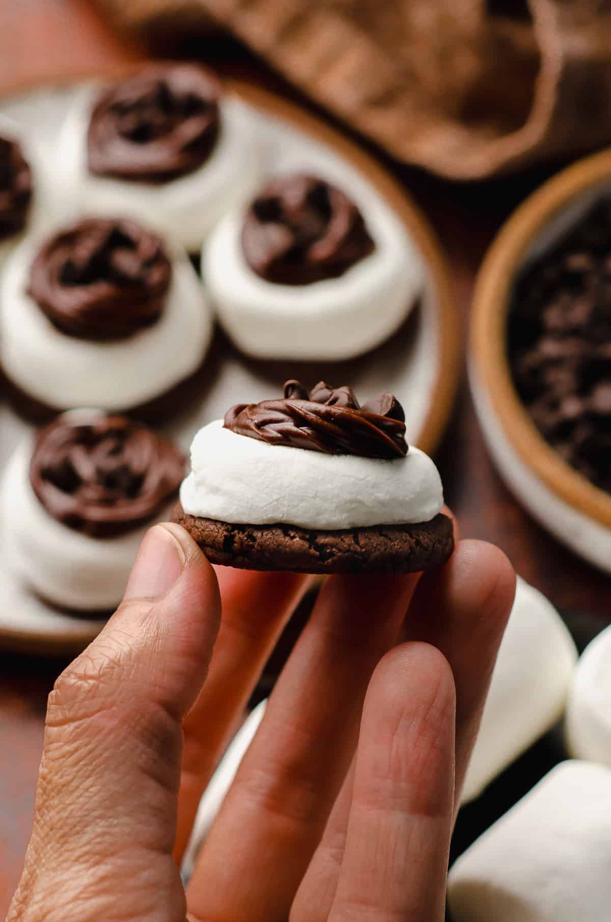 a hand holding a bite size hot cocoa cookie