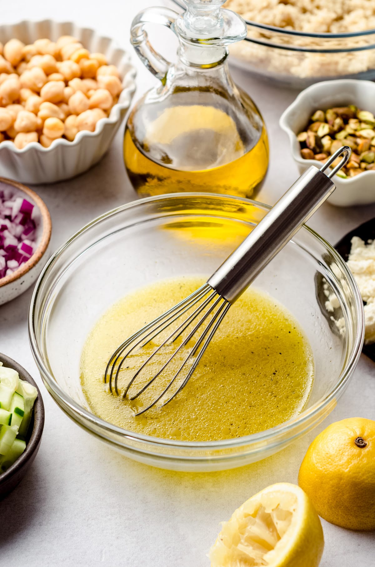 Simple salad dressing made from lemon juice, olive oil, salt and pepper in a glass bowl with a whisk sitting in it.