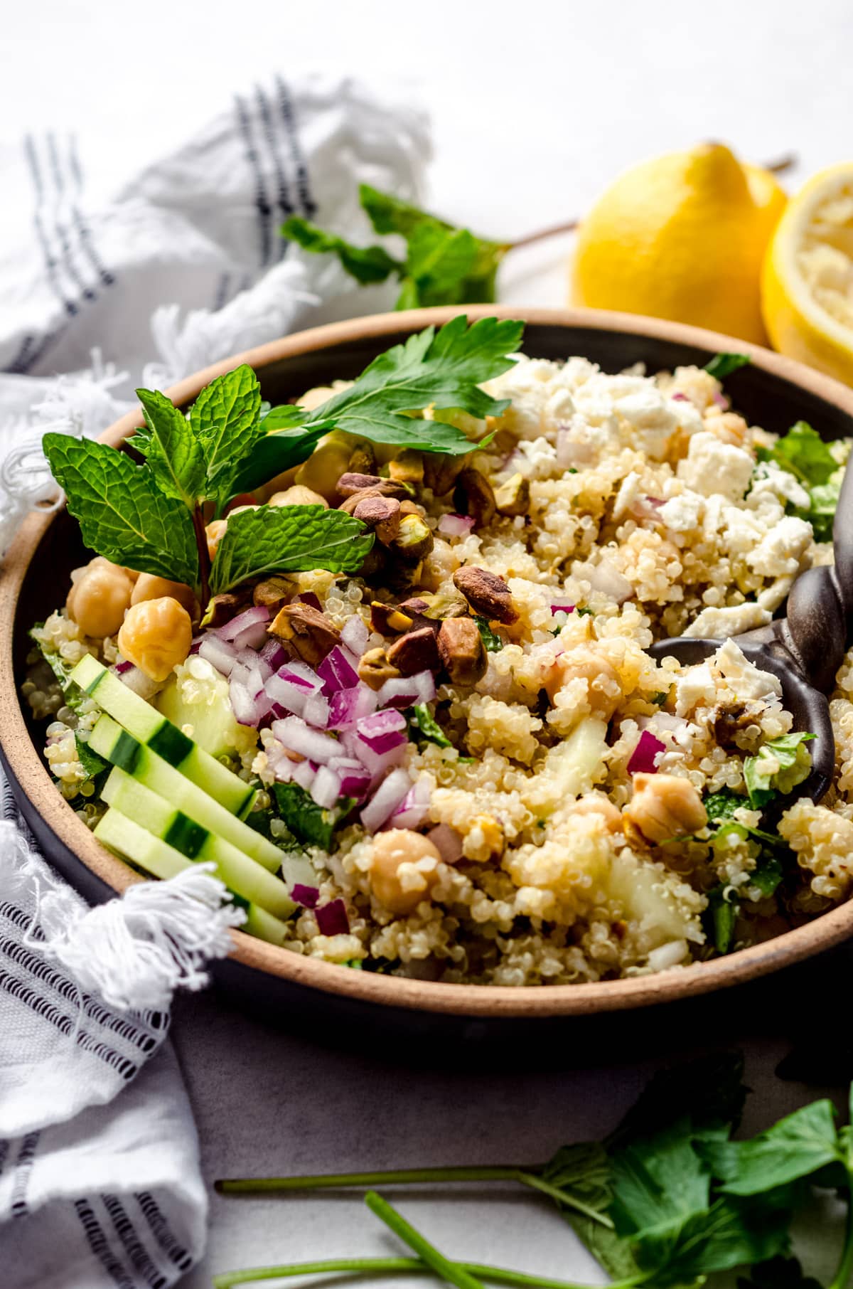 Jenifer Aniston salad in a wooden bowl. Topped with extra mint leaves with a wooden spoon about to scoop up a piece.