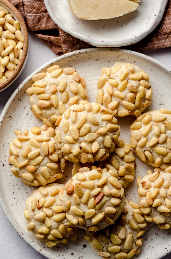 A plate of pignoli cookies coated in pine nuts.