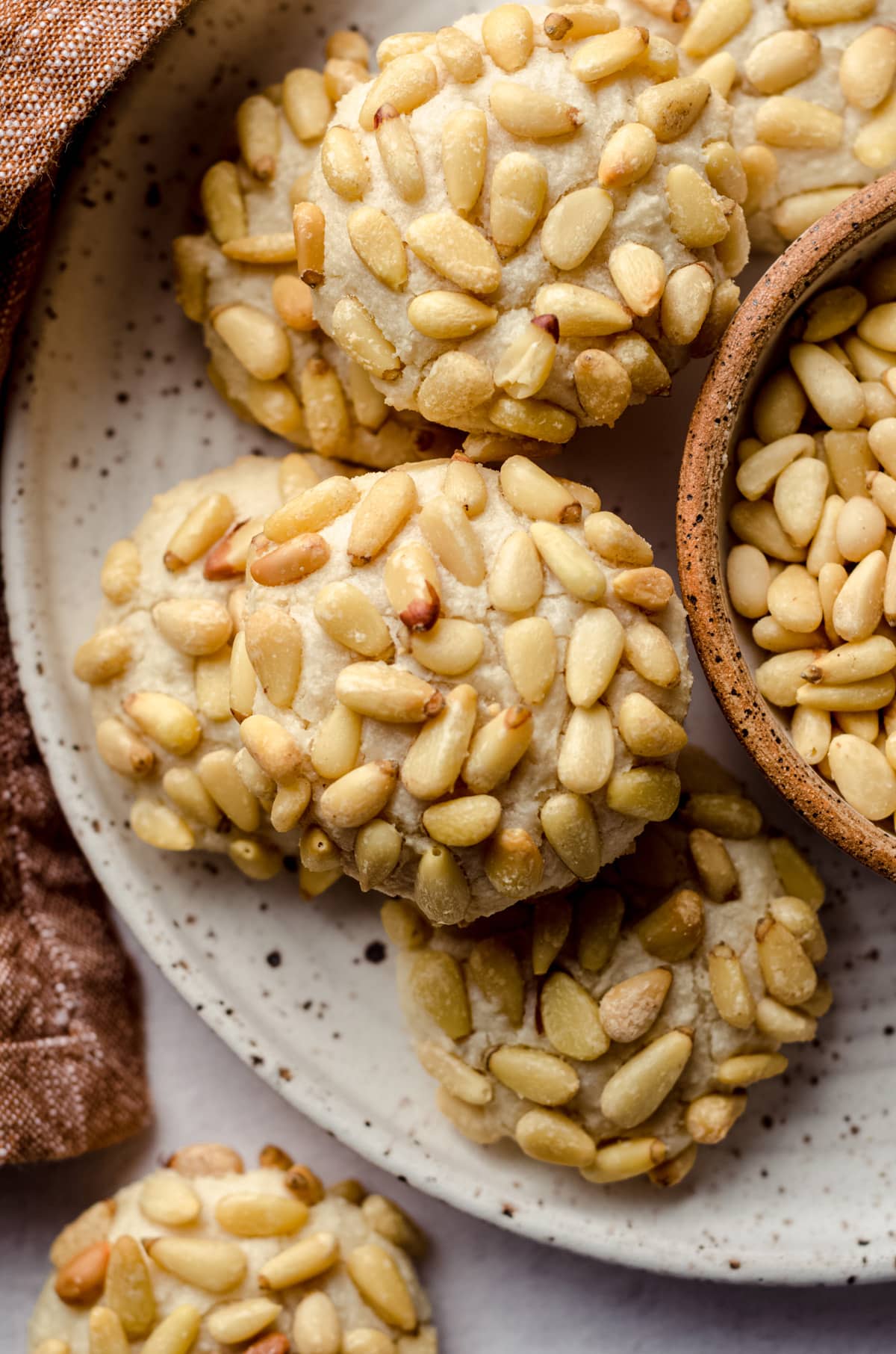 A plate of pignoli cookies coated in pine nuts.
