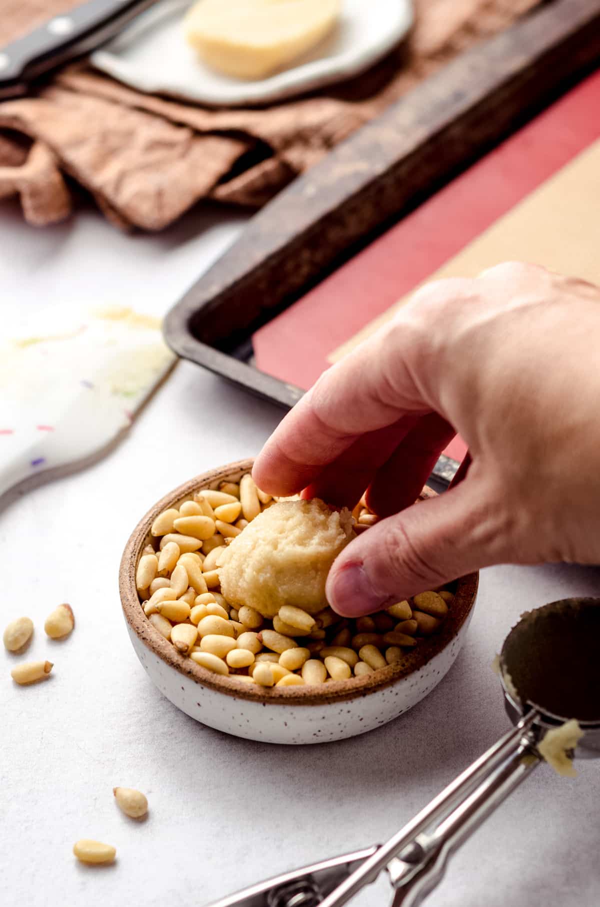 Coating a cookie dough ball with pine nuts.
