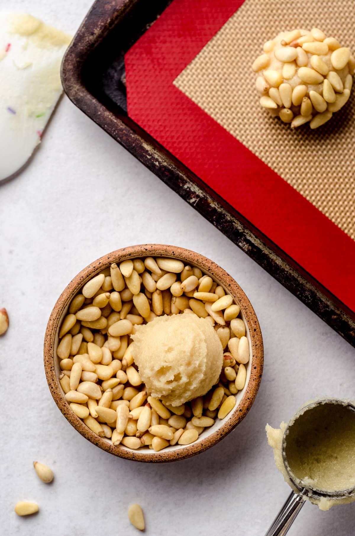 A small bowl of pine nuts with raw cookie dough dropped in.