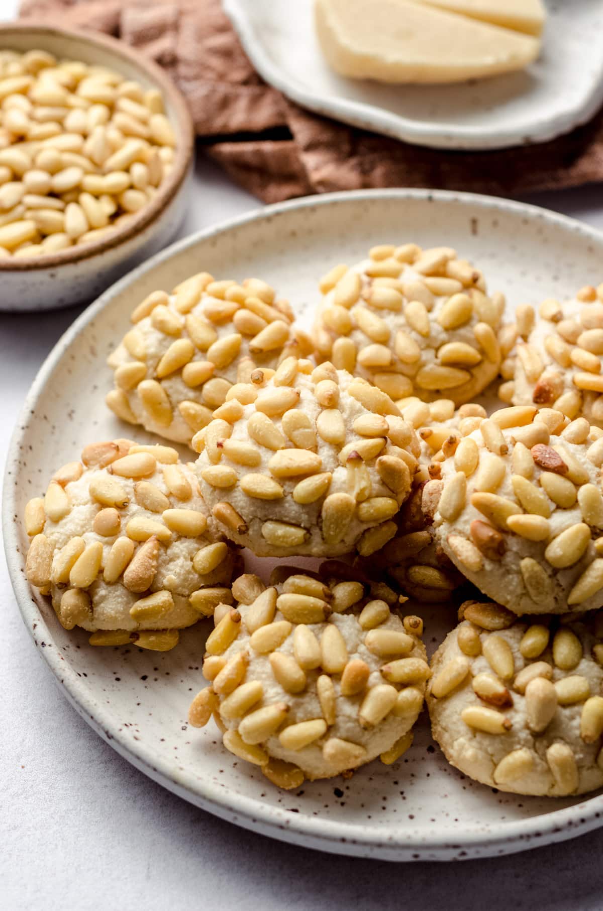 A plate of pignoli cookies coated in pine nuts.