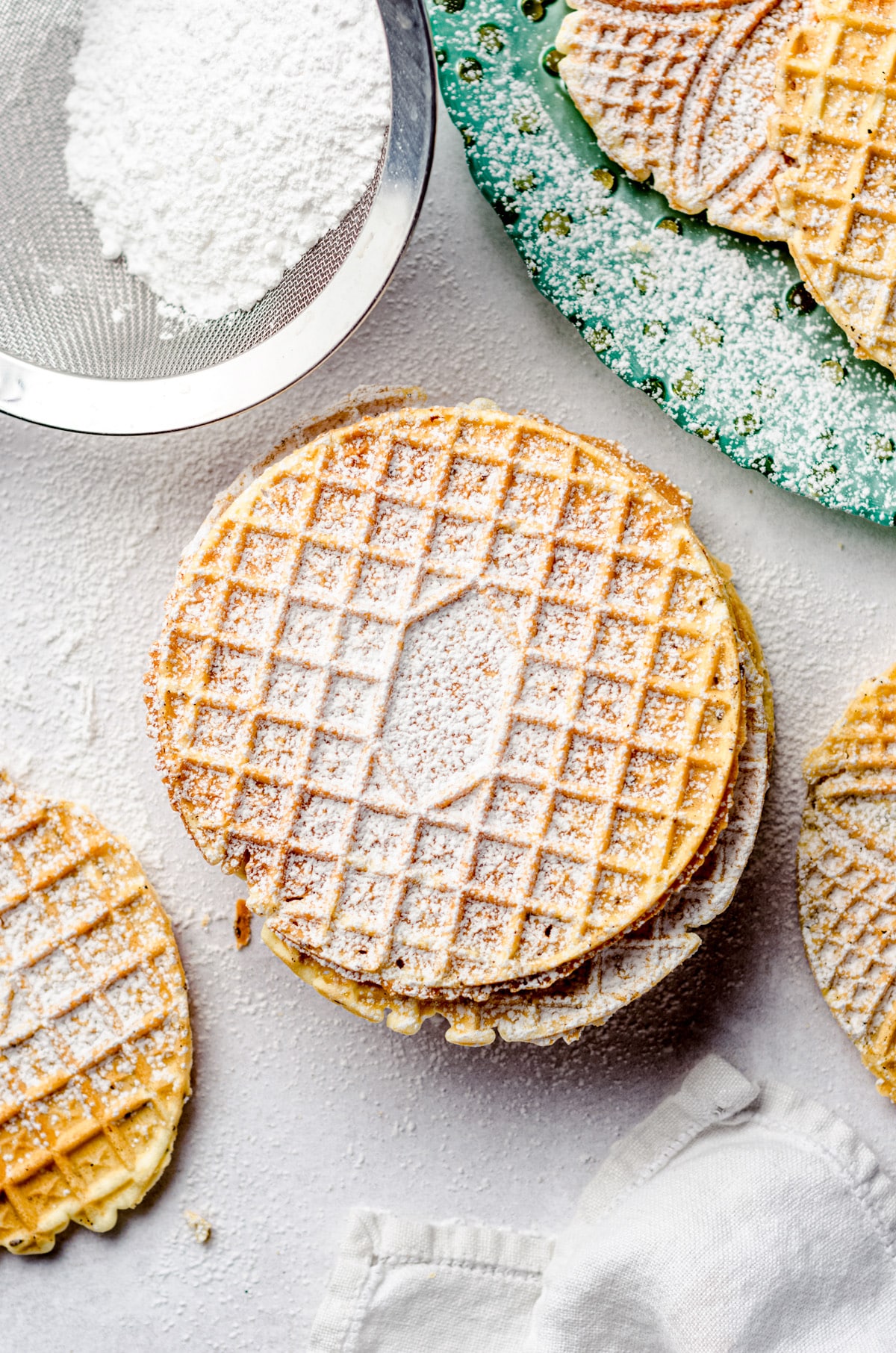 A stack of Italian cookies sprinkled with powdered sugar.