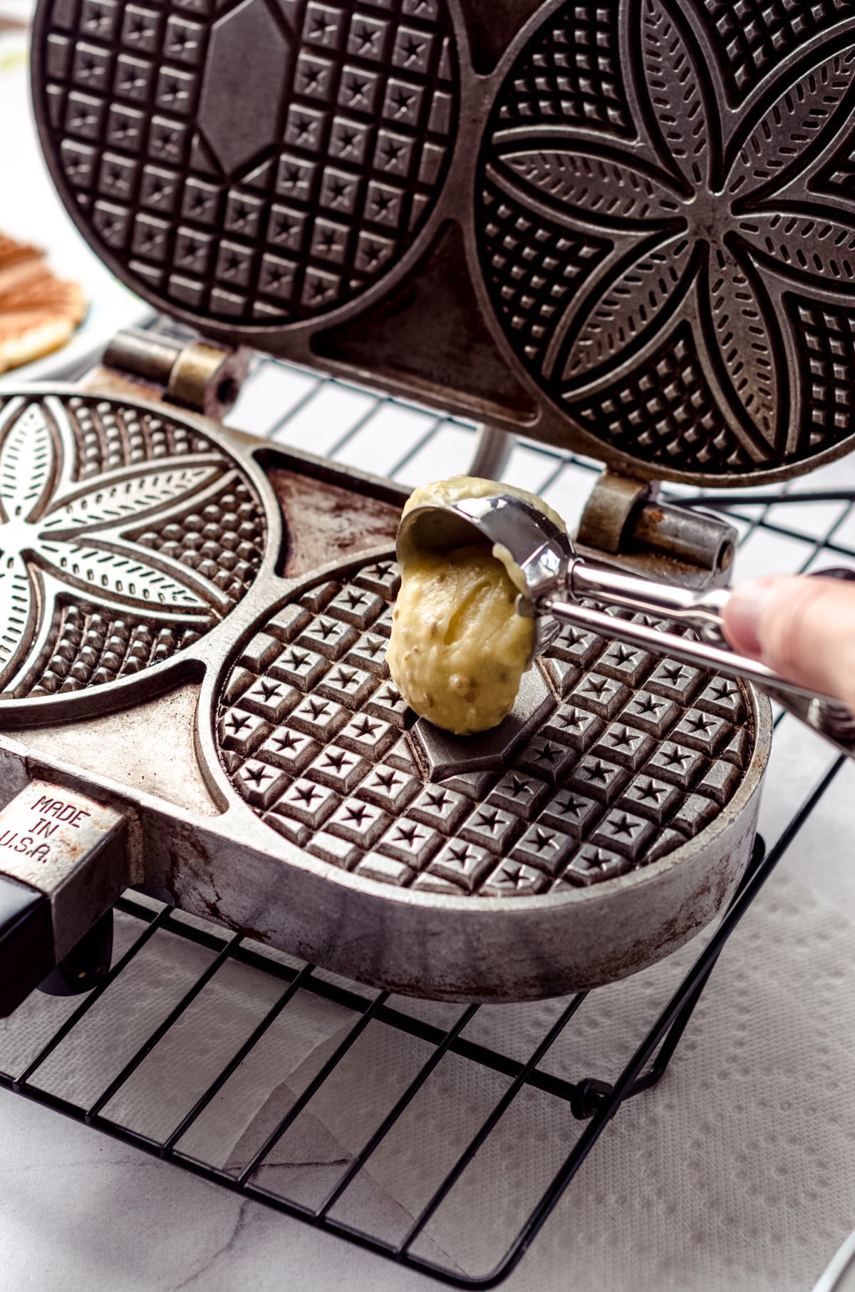 Adding batter to a pizzelle maker.