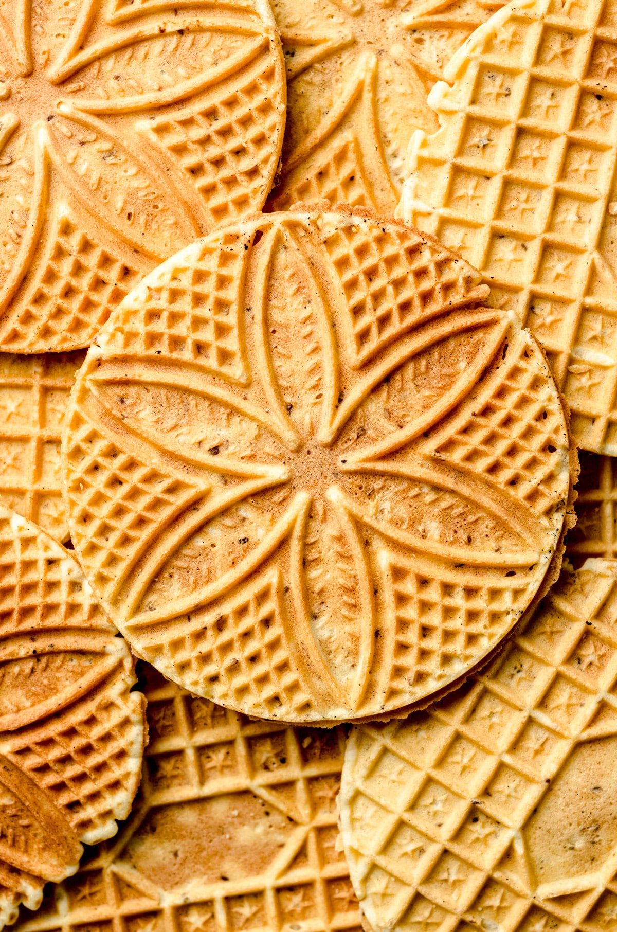 Pizzelle cookies layered on top of each other with a close up of the imprint.