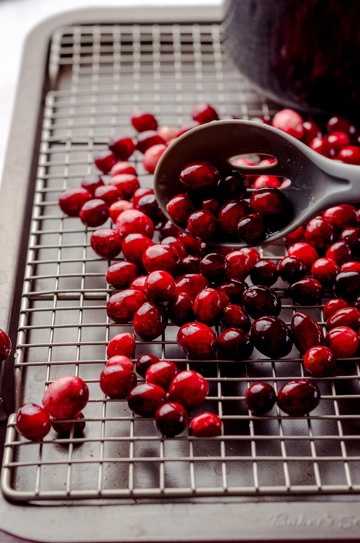 spooning sugared cranberries on a wire rack