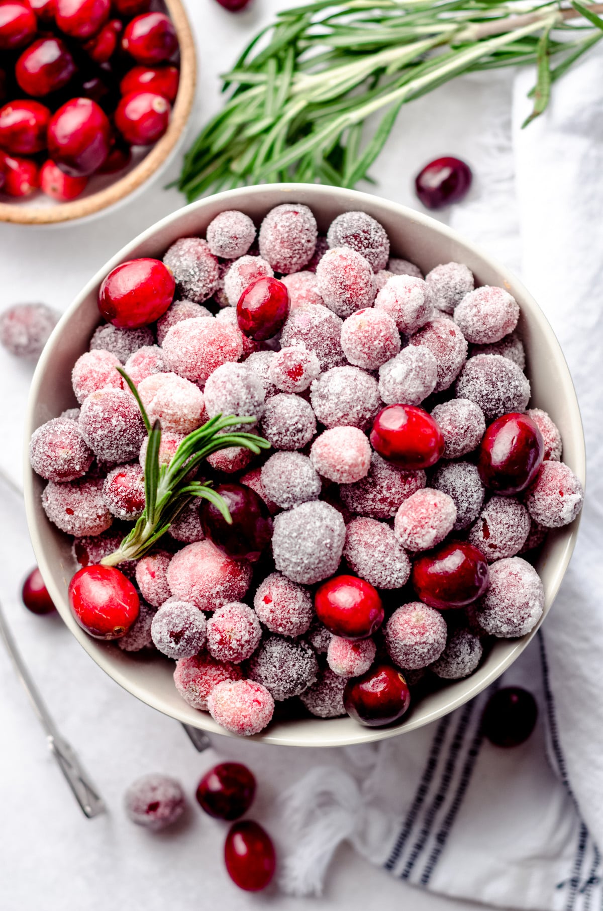 aerial photo of a bowl of sugared cranberries with rosemary sprigs