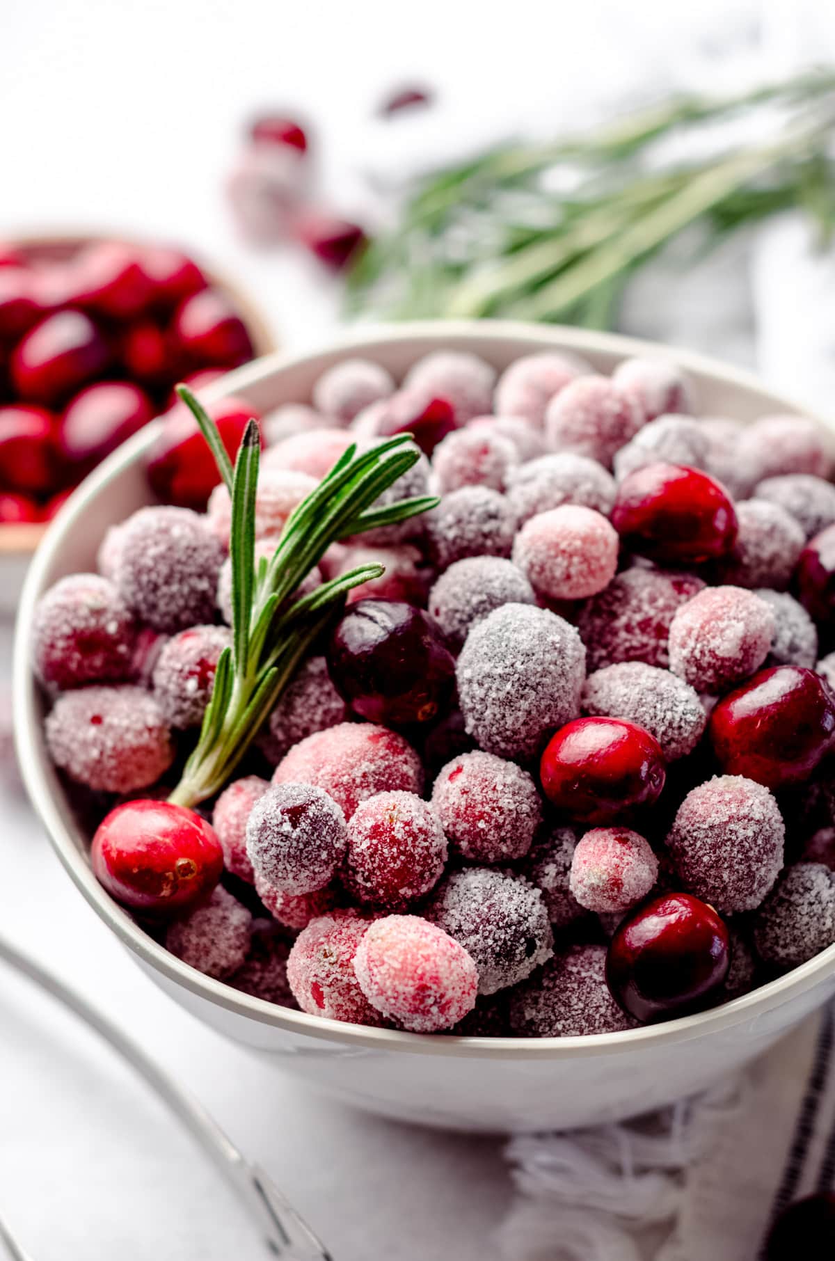 bowl of sugared cranberries with rosemary sprigs