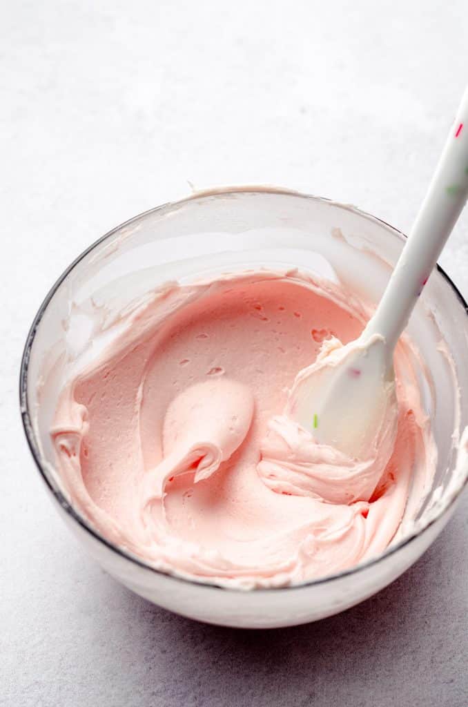 bowl of pink frosting with a spatula