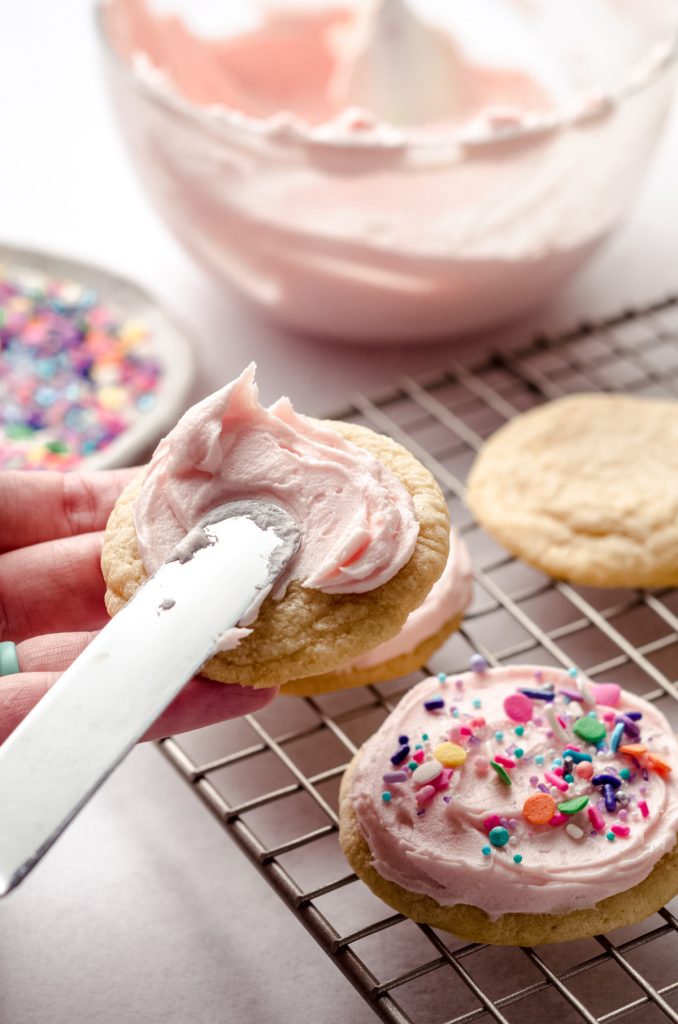 spreading frosting on a sugar cookie