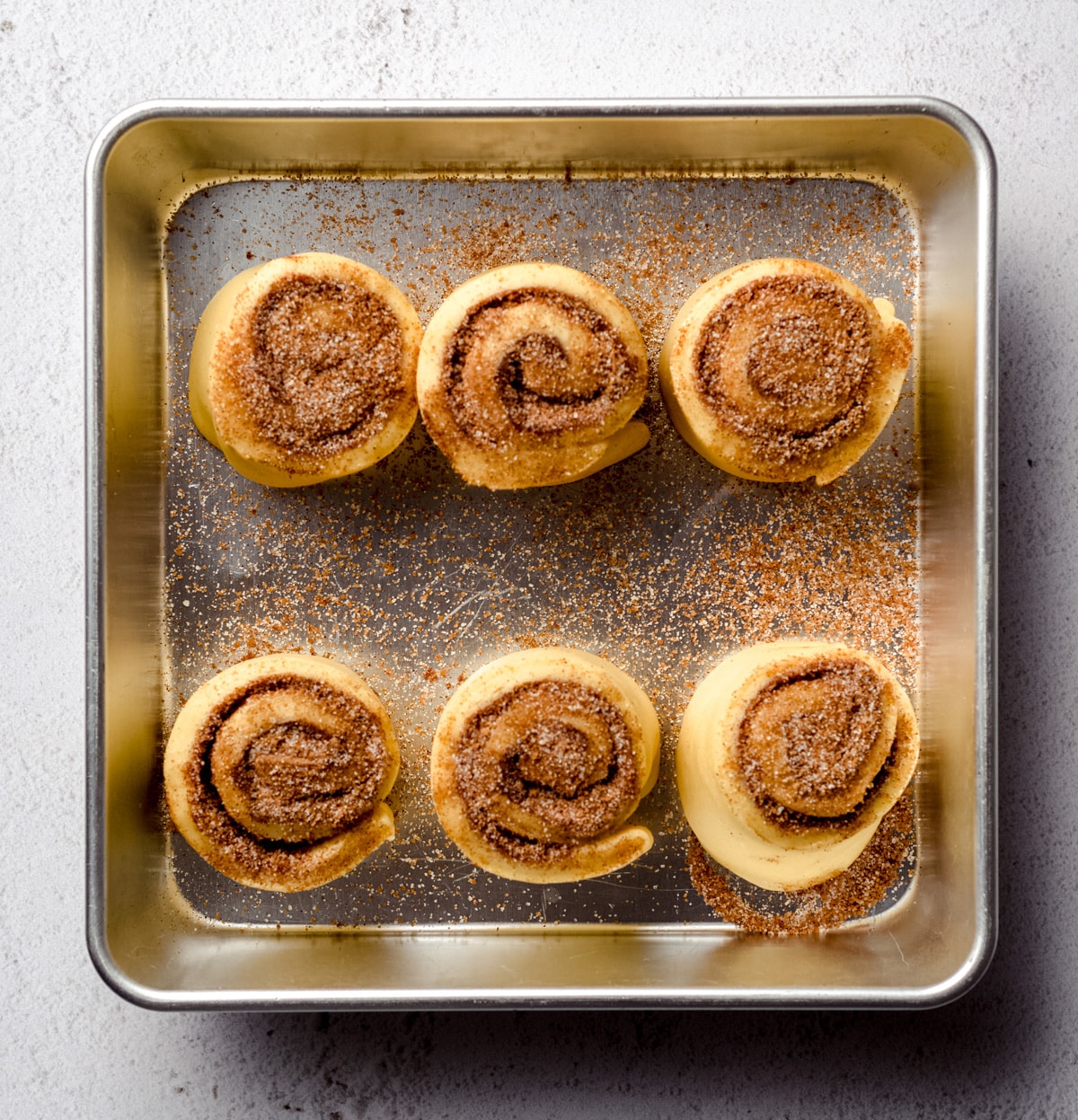 Small batch cinnamon rolls in a baking dish after they have risen.