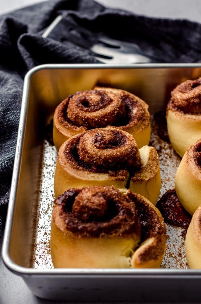 Baked cinnamon rolls in a square baking pan.