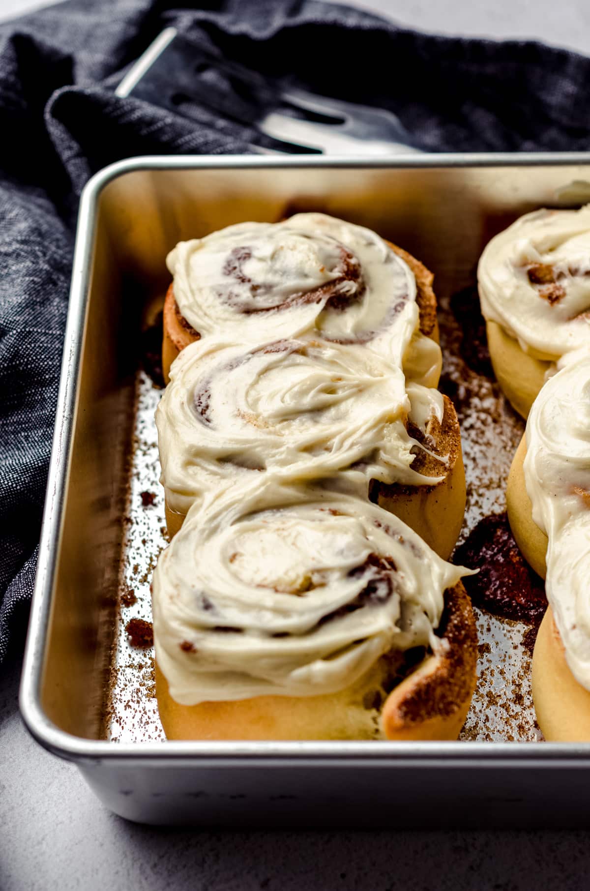 Small batch cinnamon rolls in a baking dish with cream cheese frosting spread on top.