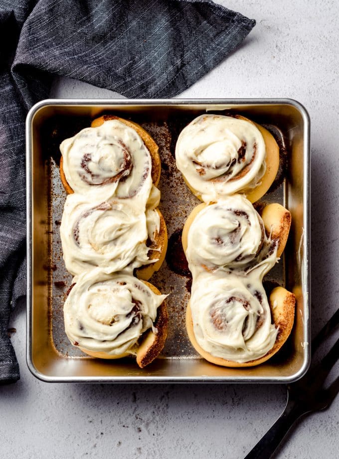 Aerial photo of small batch cinnamon rolls in a baking dish with cream cheese frosting spread on top.