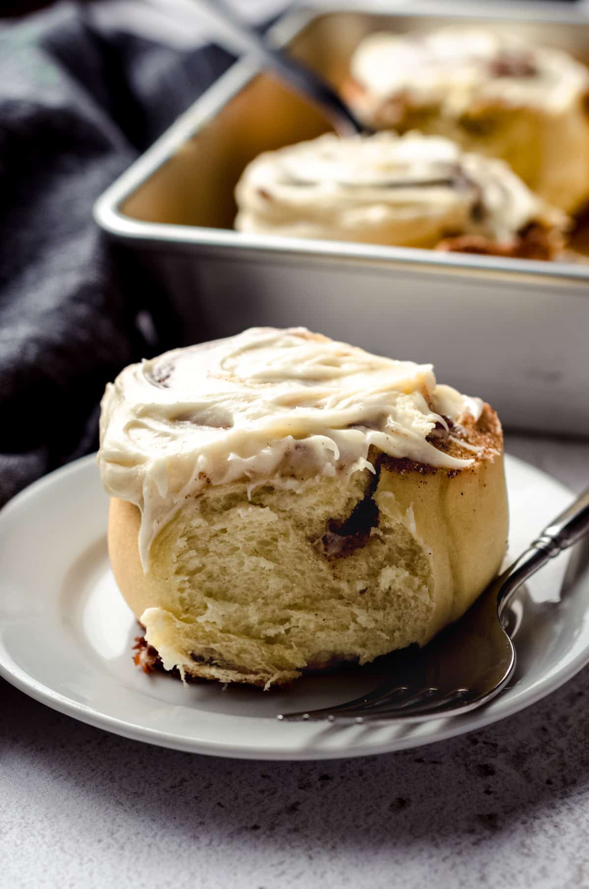 Cinnamon roll sitting on a plate with a fork.