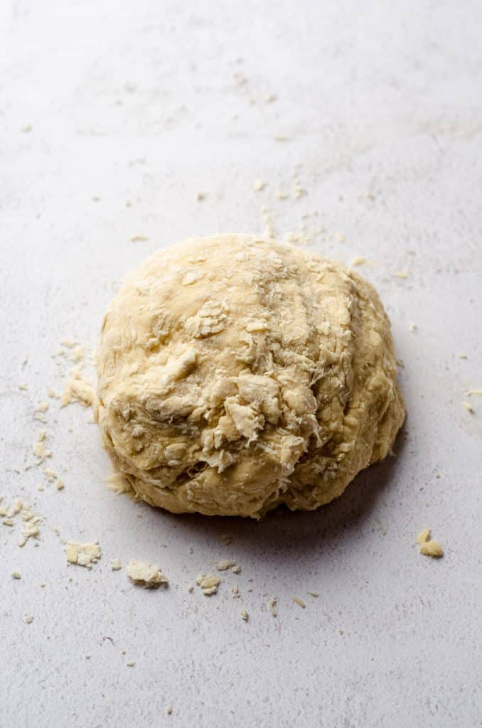 A ball of shaggy cinnamon roll dough on a surface.