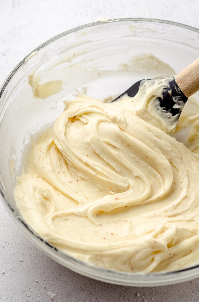 Brown butter cream cheese frosting in a glass bowl with a spatula.