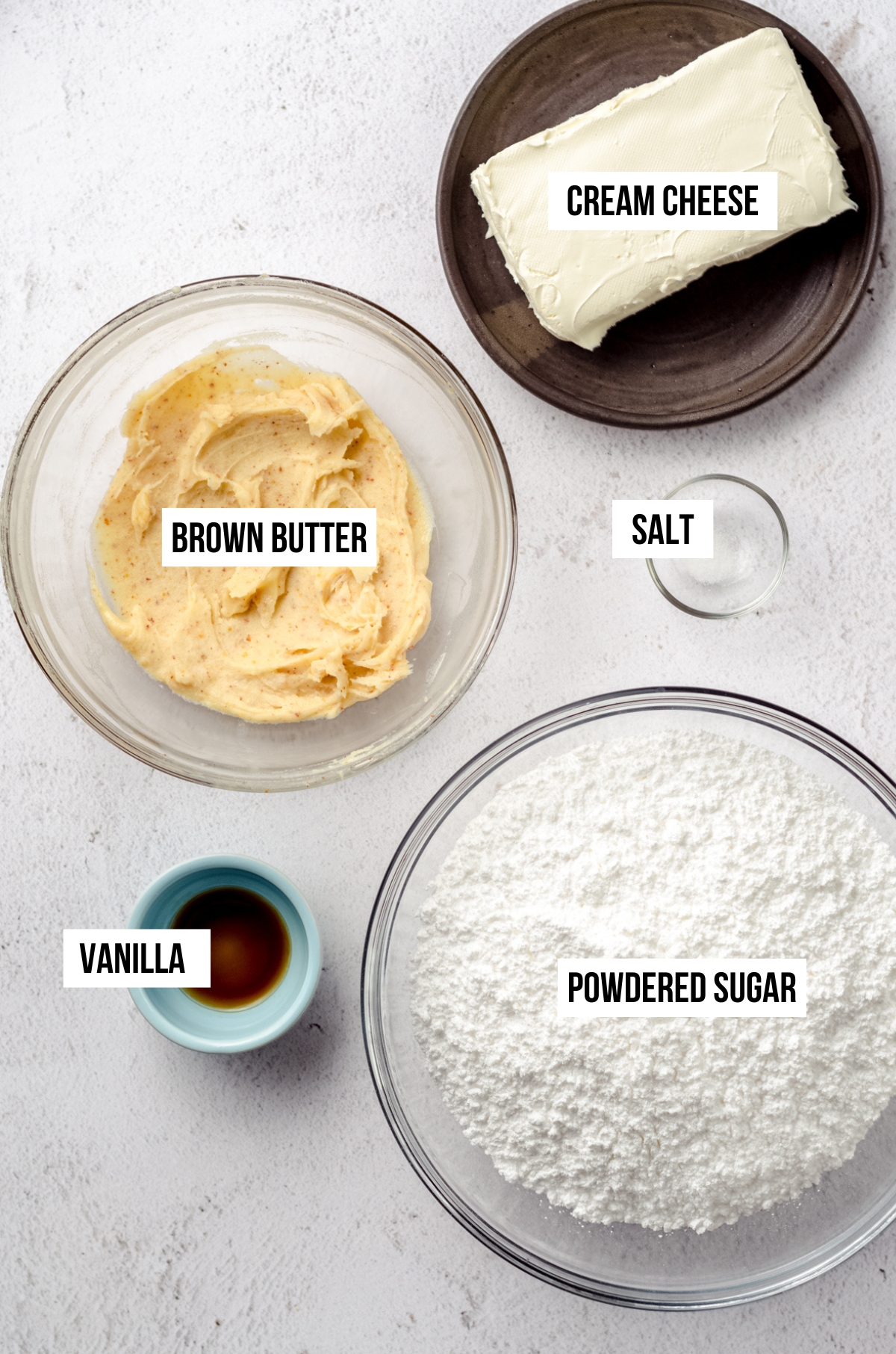 Aerial photo of the ingredients needed for brown butter cream cheese frosting. The ingredients have text overlay.