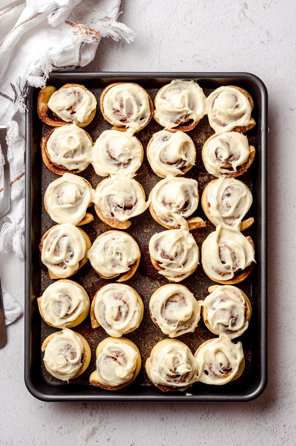 Aerial photo of mini cinnamon rolls with cream cheese frosting in a baking dish.