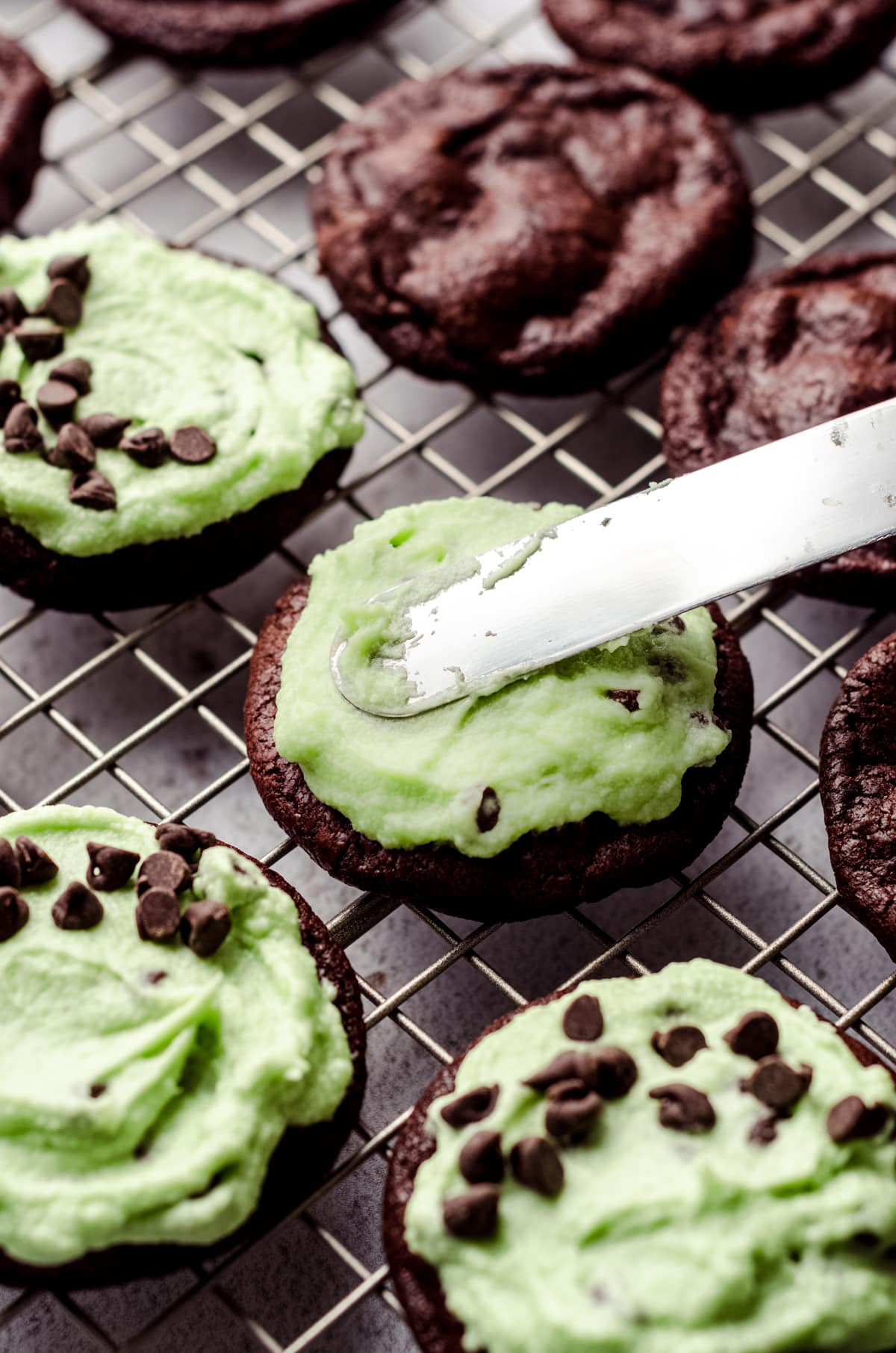 frosting being applied to cookies with an offset spatula. 