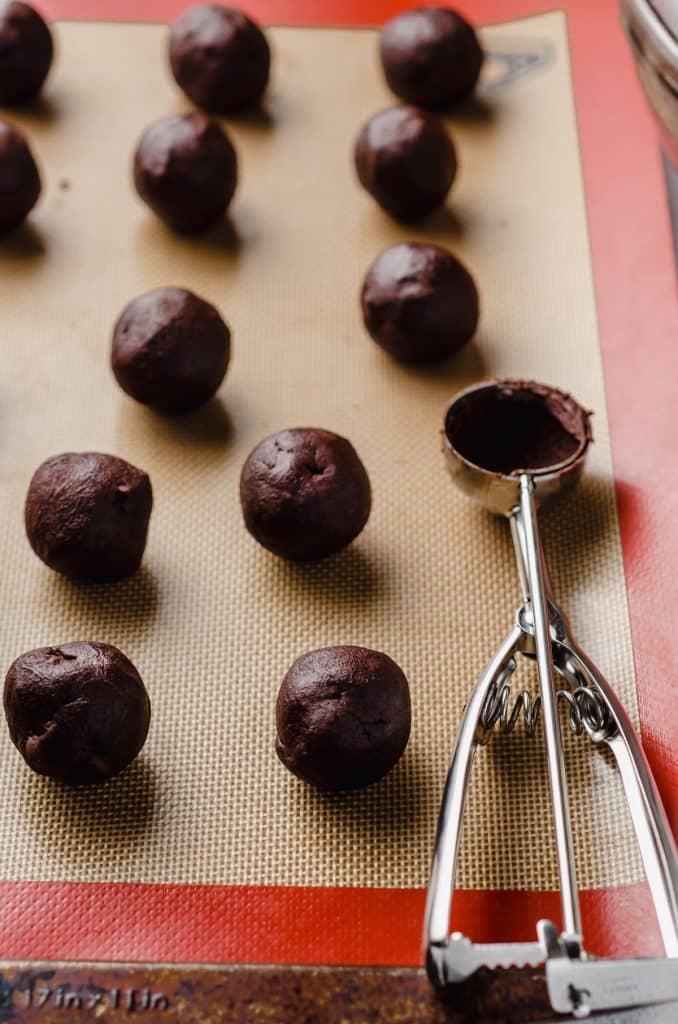 double chocolate cookie dough balls lined up on a baking sheet. 