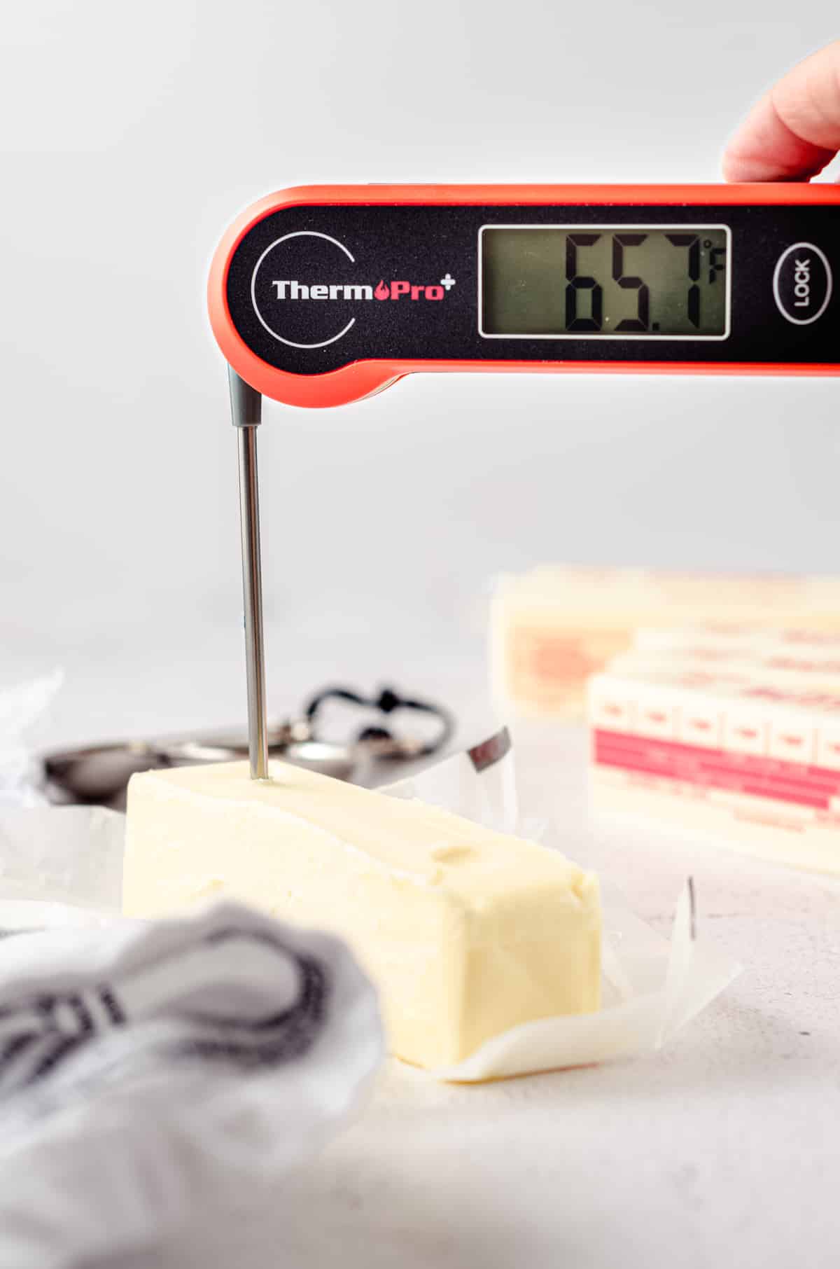 An instant read thermometer stuck into a stick of butter to test the internal temperature.