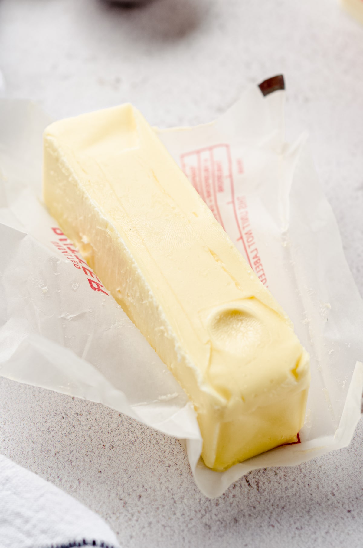 A stick of room temperature butter with a finger imprint indicating it's ready to use.