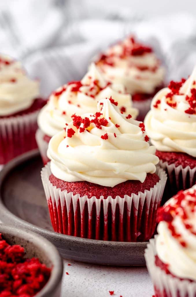 A red velvet cupcake with cream cheese frosting on a plate.