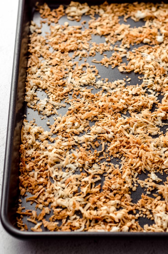 Shredded coconut spread out on a sheet pan after being toasted.