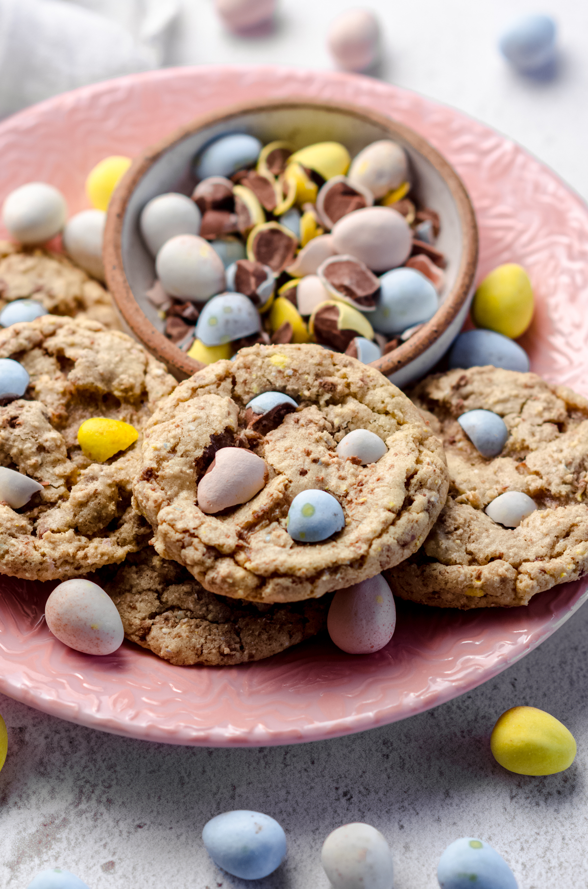 Mini egg cookies on a plate with a bowl of crushed mini eggs.