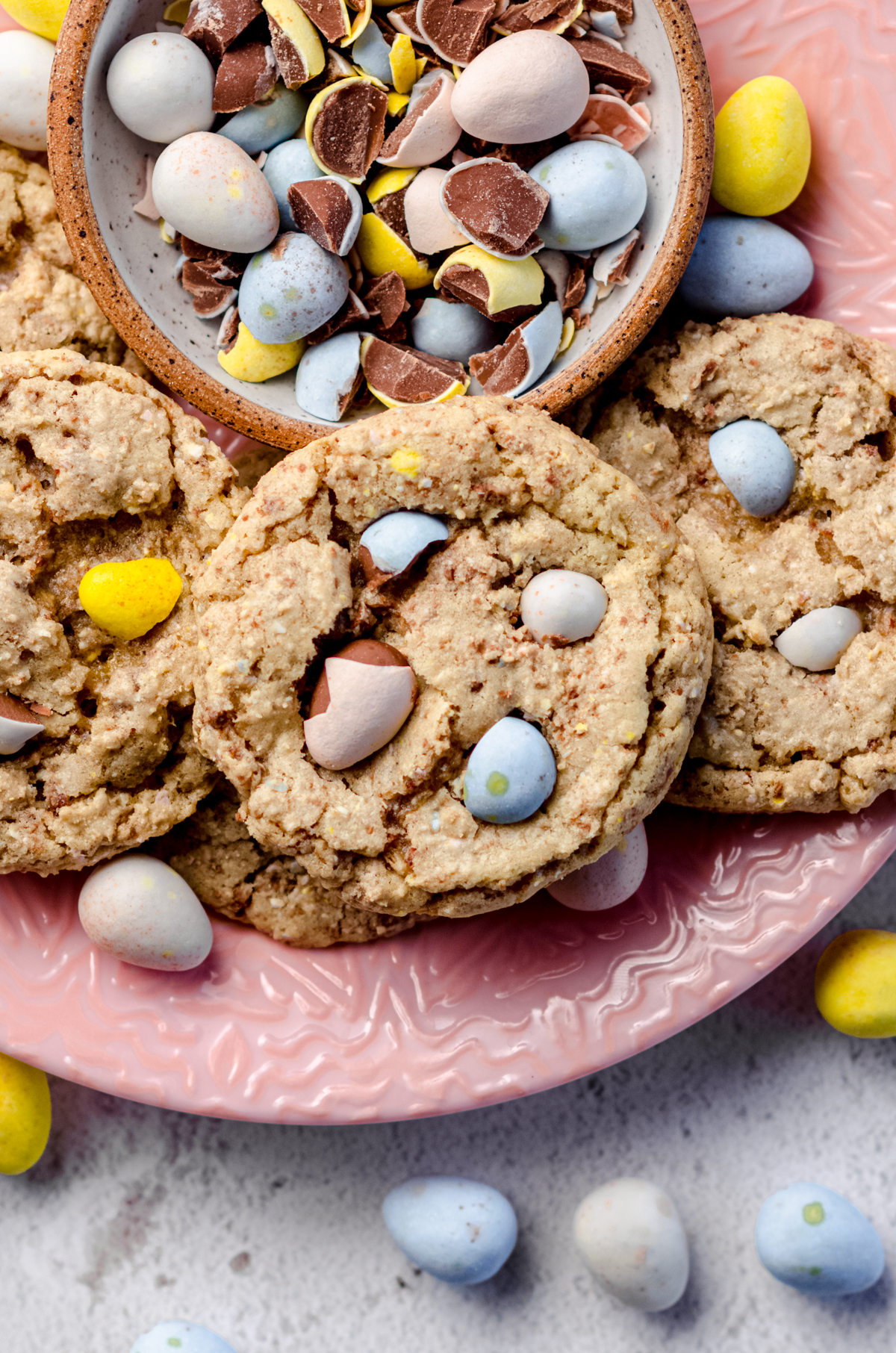 Aerial photo of mini egg cookies on a pink plate with a bowl of crushed mini eggs.