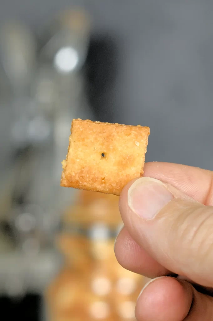 Fingers holding a sourdough cheese cracker.