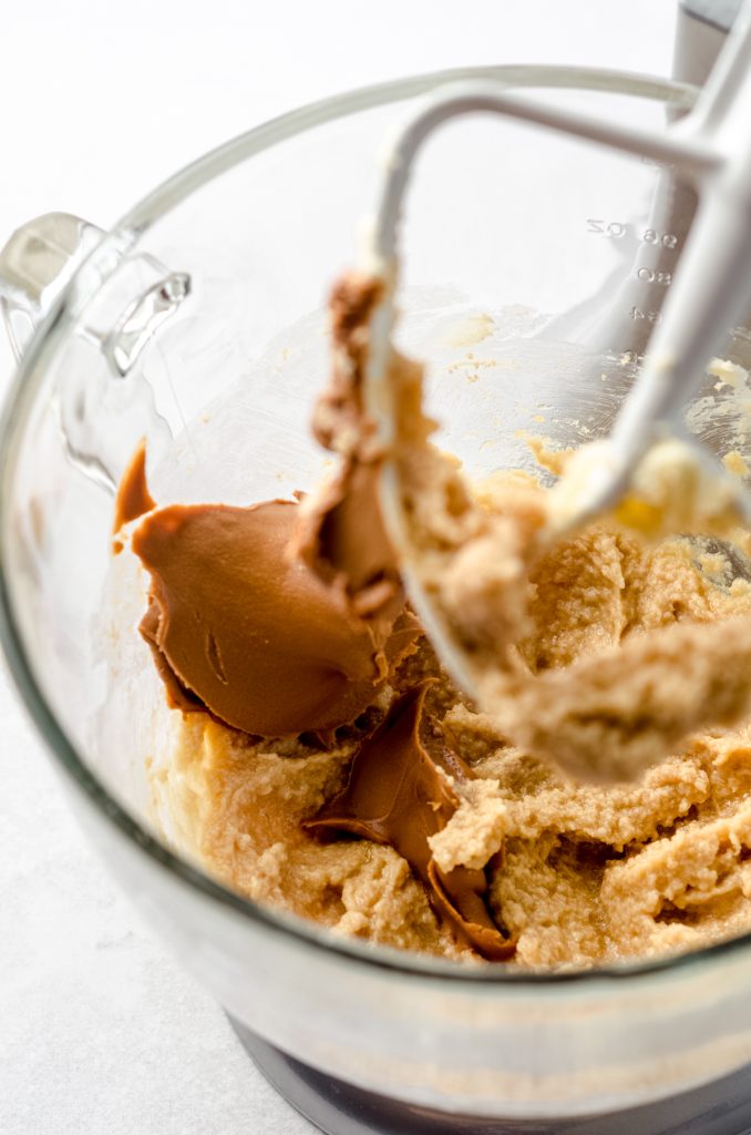 Cookie dough in a mixer with Biscoff cookie butter being added to it.