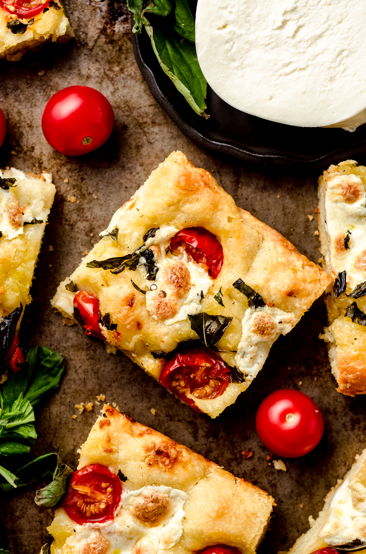 Aerial photo of a slice of caprese focaccia on a baking sheet.