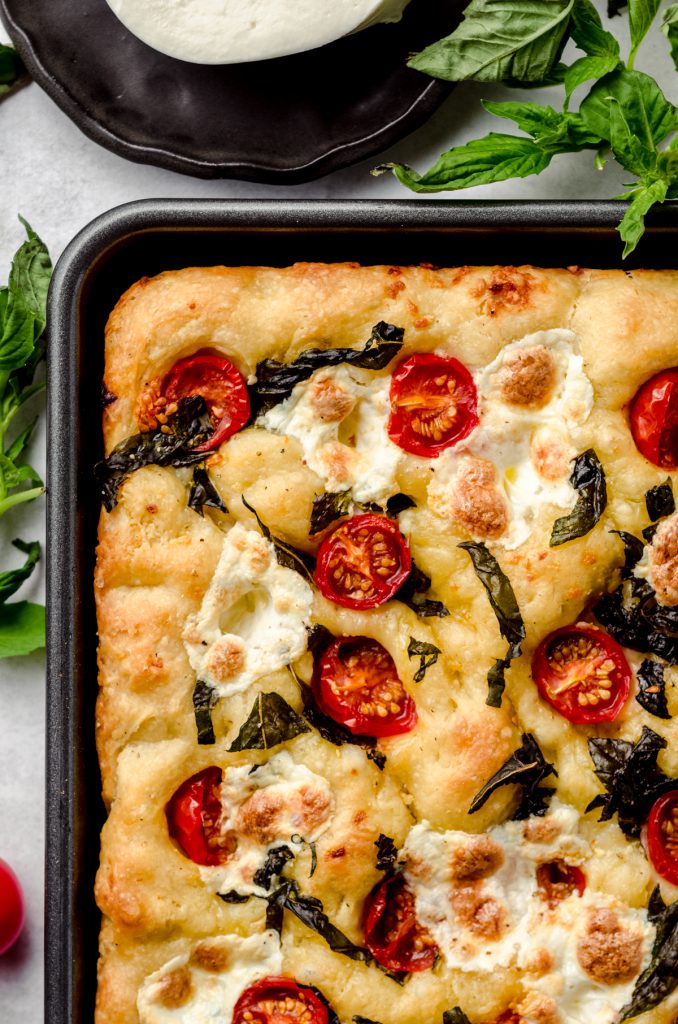 Aerial photo of the corner of baked caprese focaccia in a baking dish.