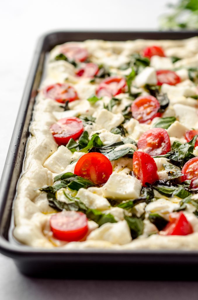 Caprese focaccia dough in a baking dish.