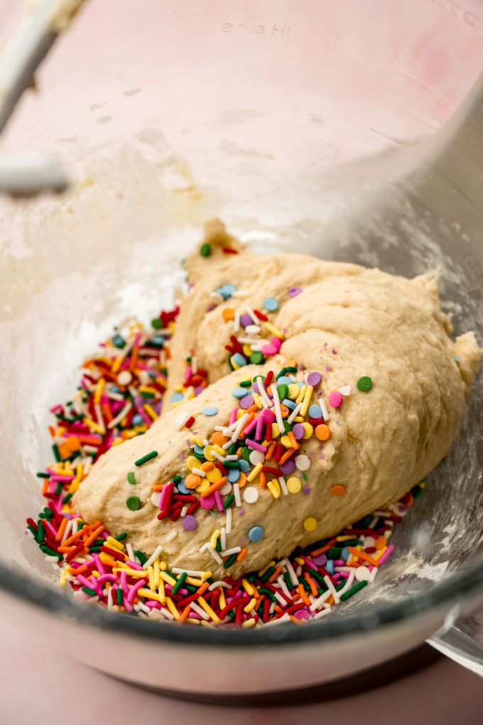 Funfetti cinnamon roll dough in the bottom of a mixing bowl.