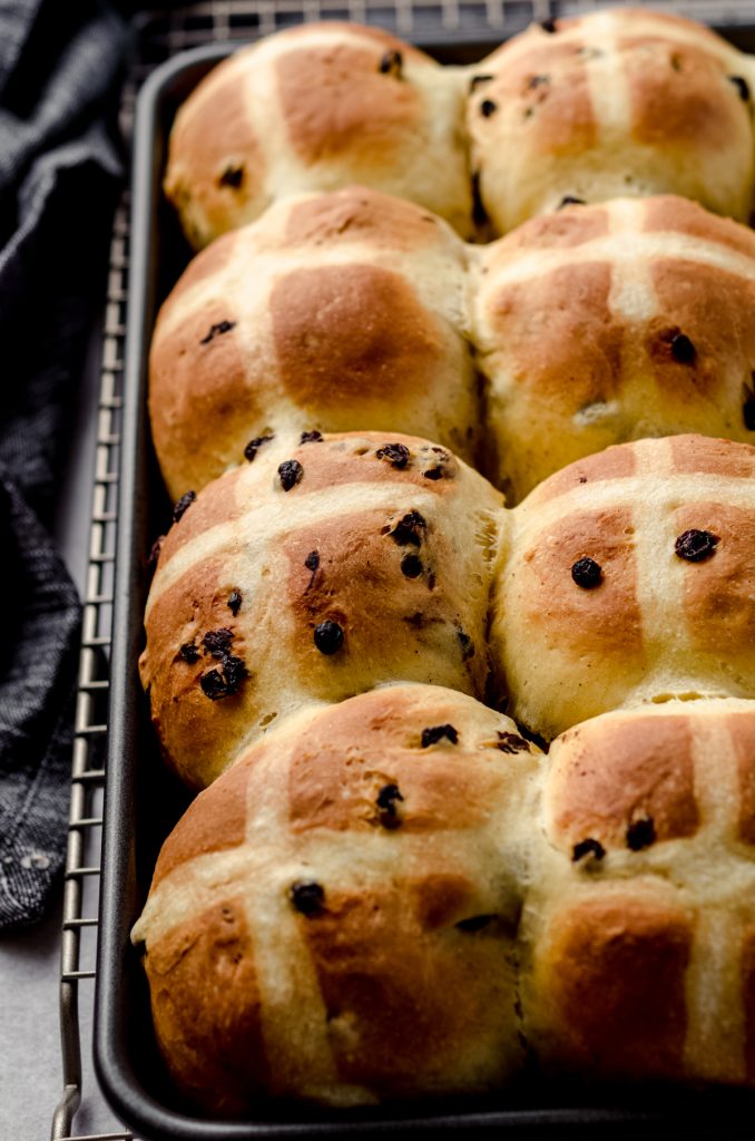 Hot cross buns baked in a pan before adding a glaze.