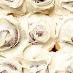 Cream cheese frosting spread on top of cinnamon rolls.